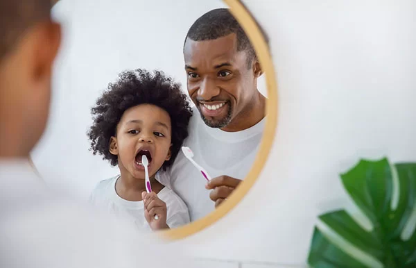 a dad and his son brushing teeth