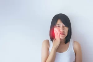 young asian lady holding her cheek due to pain